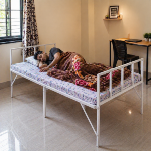 White metal single bed in a small modern bedroom with person sleeping, lifestyle room setup for compact apartment living